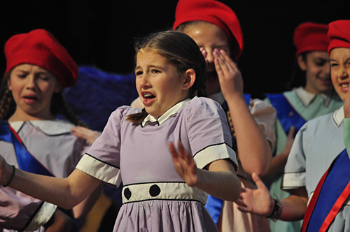 Girl in purple dress acting on stage in a musical