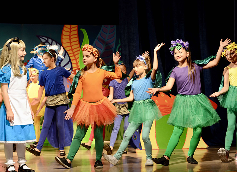 Children dancing dressed as flowers in Alice in wonderland
